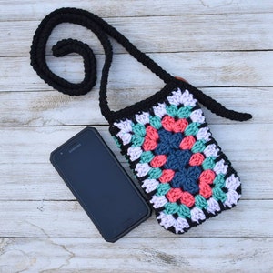May include: A crocheted phone bag with a black strap and a colourful granny square design. The bag is made with pink, green, blue, and white yarn.