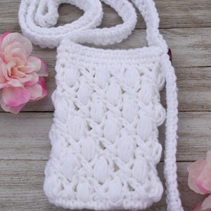 May include: White crocheted crossbody bag with a textured, puffy design. The bag has a long strap and is made with a white yarn.