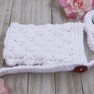 May include: White crocheted crossbody bag with a button closure and a long strap. The bag has a textured, puffy design.