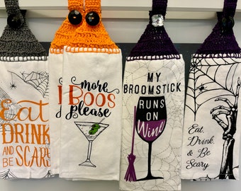 Op de afbeelding: Vier Halloween-keukendoeken met gehaakte tops. De doeken tonen zinnen als "Eat, Drink, & Be Scary" en "More Boos Please" met martini- en wijnglasillustraties. De gehaakte tops zijn grijs, oranje en paars.