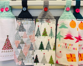 Puede incluir: Un conjunto de cinco paños de cocina colgantes con la parte superior de ganchillo y cierres de botón. Los paños presentan varios diseños de árboles de Navidad y motivos festivos en rosa, verde, gris y blanco. Un paño tiene el texto "Merry Everything".