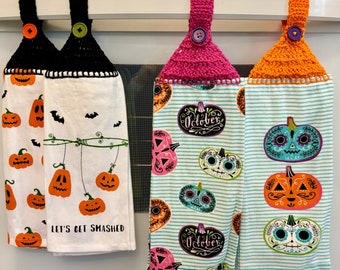Puede incluir: Cuatro paños de cocina con temática de Halloween colgando de una barra blanca. Dos toallas tienen diseños de calabazas naranjas y el texto "Let's Get Smashed". Las otras dos tienen diseños de calaveras de azúcar y calabazas con la palabra "October".