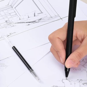 May include: A black pen with a clear plastic tip is being used to draw on a sheet of paper with a pencil sketch of a room. The pen is held in a hand.