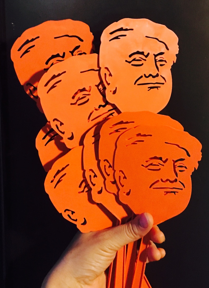 Peut inclure: Un ensemble de six silhouettes en plastique orange d&eacute;coup&eacute;es d'un visage humain. Les d&eacute;coupes sont tenues dans une main.