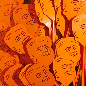 Peut inclure: Gros plan sur un tas de raquettes &agrave; mouches en plastique orange avec une silhouette de visage sur chacune. Les visages ont tous des expressions diff&eacute;rentes.