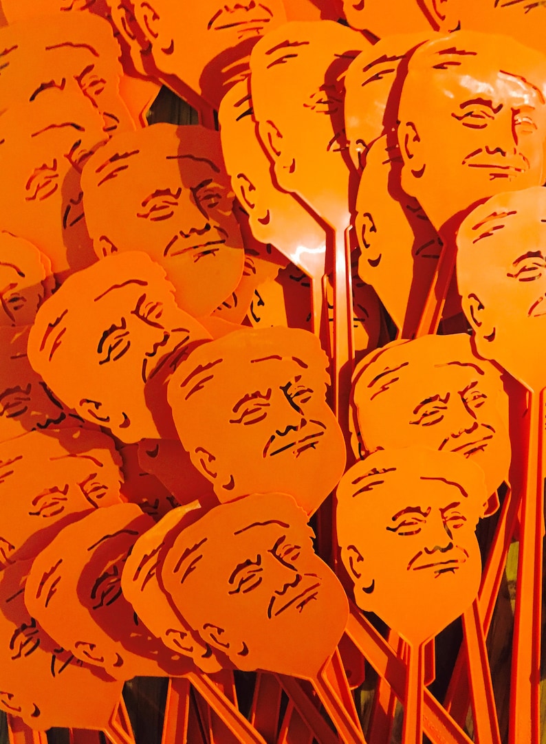 Peut inclure: Gros plan sur un tas de raquettes &agrave; mouches en plastique orange avec une silhouette de visage sur chacune. Les visages ont tous des expressions diff&eacute;rentes.