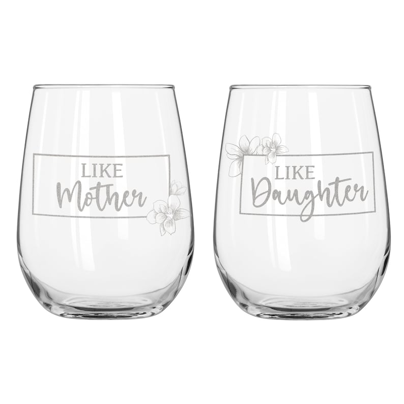 May include: Two clear glass wine glasses with the text "Like Mother" and "Like Daughter" etched on them. Each glass has a floral design.