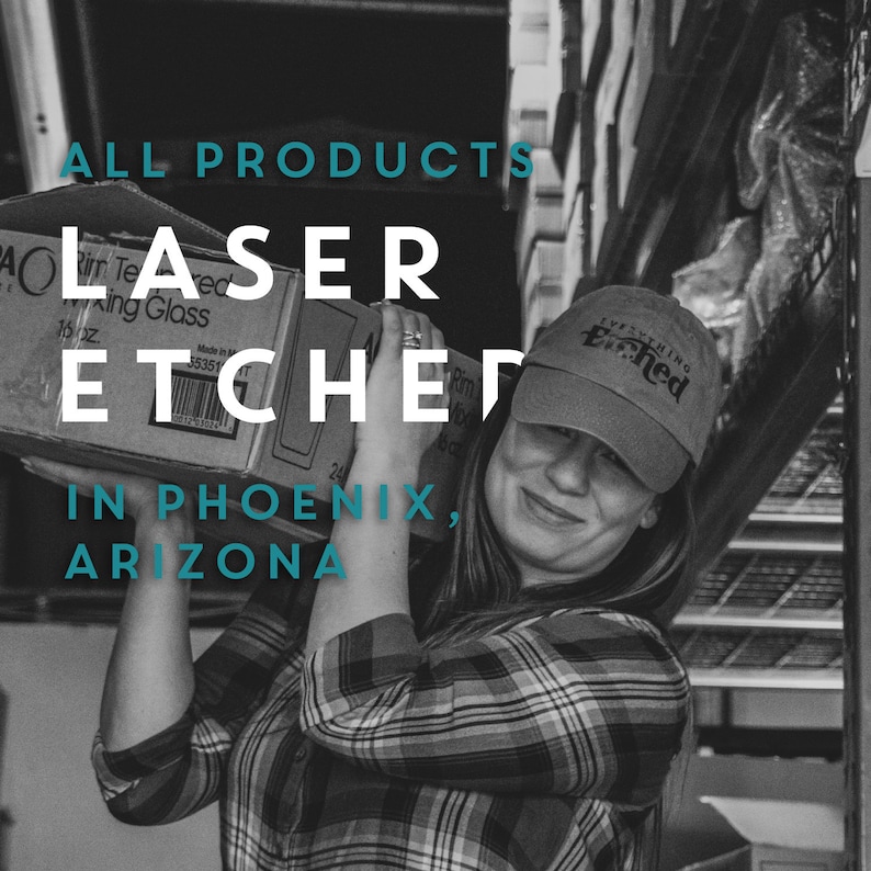 May include: A woman is holding a cardboard box with the text "ALL PRODUCTS LASER ETCHED IN PHOENIX, ARIZONA" printed on it. She is wearing a black and white plaid shirt and a black baseball cap with the text "EVERYTHING ETCHED" printed on it.