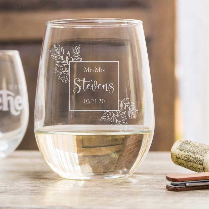 May include: A clear glass wine glass with a floral design and the text "Mr. + Mrs. Stevens 03.21.20" etched on the side.