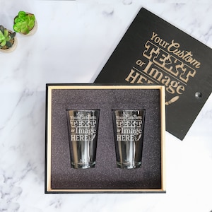 May include: Two clear glass pint glasses with a black wooden box. The glasses are engraved with the text "Your Custom TEXT or Image HERE".
