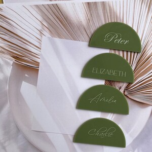 May include: Four green half-circle place cards with white calligraphy names: Peter, Elizabeth, Amelia, and Charlie.