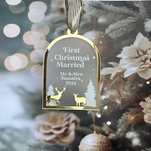 May include: A gold-framed Christmas ornament with the text "First Christmas Married" and the names "Mr & Mrs Samalra 2024". The ornament features deer and tree silhouettes. A gold ribbon is attached for hanging.