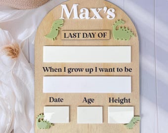 May include: A wooden growth chart with a dinosaur theme. It has a white inscription that says "Max's" at the top, followed by "Last Day Of", "When I grow up I want to be", "Date", "Age", and "Height".