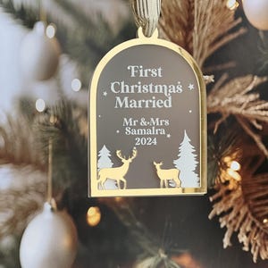 May include: A gold-framed Christmas ornament with the text "First Christmas Married" and the names "Mr & Mrs Samalra 2024". The ornament features gold deer and white trees.