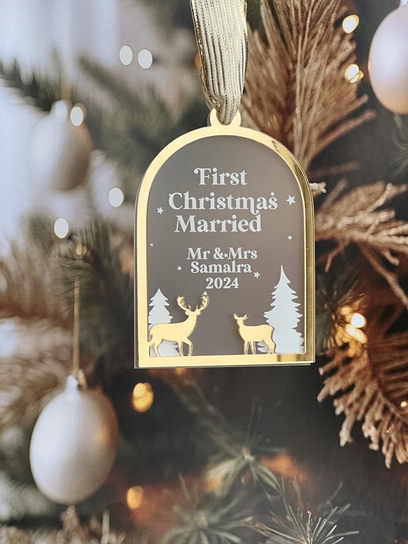 May include: A gold-framed Christmas ornament with the text "First Christmas Married" and the names "Mr & Mrs Samalra 2024". The ornament features gold deer and white trees.