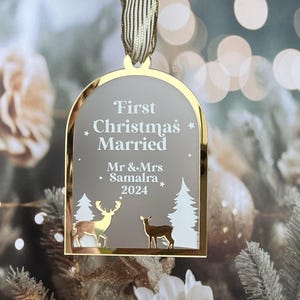 May include: A gold-framed Christmas ornament with a ribbon. The ornament has the text "First Christmas Married" and "Mr & Mrs Samalra 2024". It features deer and tree silhouettes, perfect for a newlywed couple's first Christmas.
