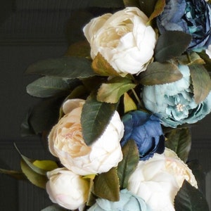 Blue peony wreath on a black door closeup.