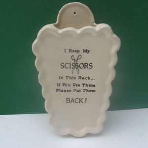 May include: White ceramic wall-mounted scissor holder with the text "I Keep My Scissors In This Rack... If You Use Them Please Put Them Back!"
