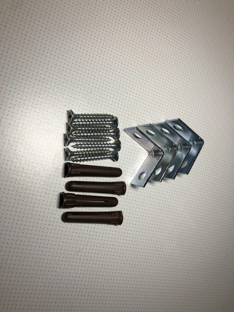 Op de afbeelding: Hardware kit met zilveren schroeven, bruine pluggen en zilveren metalen hoekbeugels. De schroeven zijn ongeveer 2,5 cm lang. De hoekbeugels hebben voorgeboorde gaten. Ideaal voor doe-het-zelf projecten.