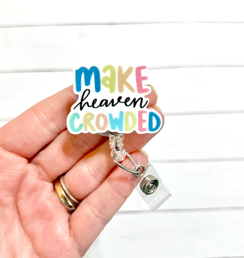 May include: A colorful badge holder with the text "Make heaven crowded" in a rainbow font. The badge holder is attached to a clear retractable badge reel.