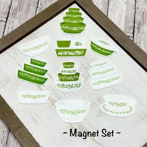 May include: A collection of green and white kitchenware magnets, including bowls and rectangular dishes, each adorned with a delicate floral pattern. The magnets are arranged on a wooden frame, with the text "~ Magnet Set ~" at the bottom.