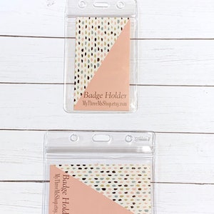 May include: Two clear plastic badge holders with a pink and white patterned insert. The insert has a diagonal line with a pink background on one side and a white background with brown, black, and green polka dots on the other side. The text "Badge Holder" and "MyThreeMsShop.etsy.com" is printed on the insert.