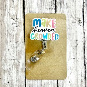 May include: A colorful badge holder with a white background and the text "Make heaven crowded" in rainbow colors.