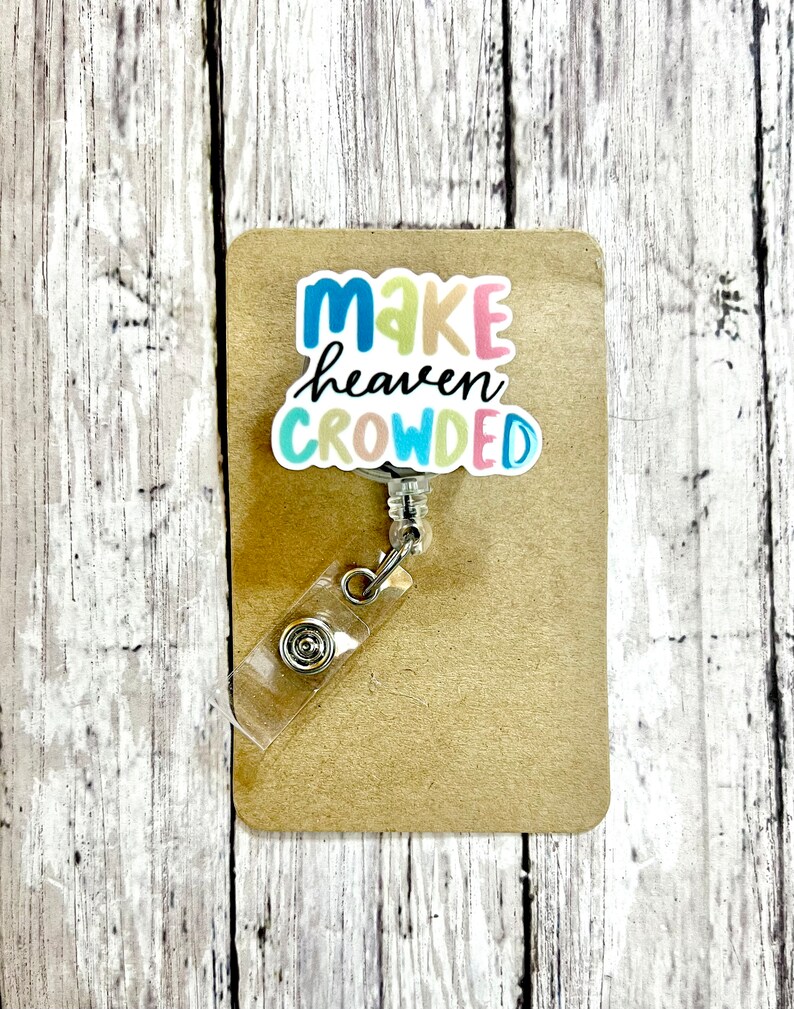 May include: A colorful badge holder with a white background and the text "Make heaven crowded" in rainbow colors.