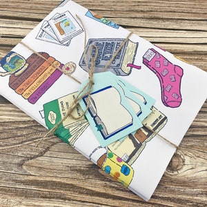 May include: A white gift wrap with a brown twine bow. The wrap features illustrations of books, socks, and mugs with book titles like "The Hobbit", "The Fellowship of the Ring", "The Two Towers", "The Return of the King", "Jane Eyre", "The Judes", "Harder We", and "Tlogers".