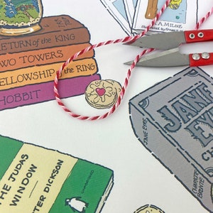 May include: A white background with a stack of books featuring the titles "The Return of the King", "The Two Towers", "The Fellowship of the Ring", and "The Hobbit". There is a red and white string, a biscuit with a red heart, and a book titled "Jane Eyre" by Charlotte Bronte.