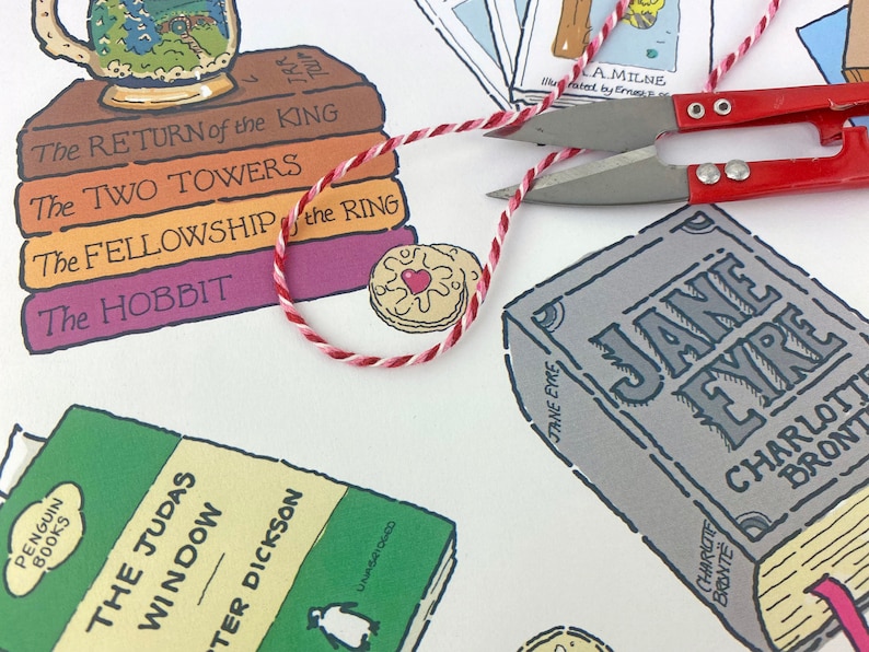 May include: A white background with a stack of books featuring the titles "The Return of the King", "The Two Towers", "The Fellowship of the Ring", and "The Hobbit". There is a red and white string, a biscuit with a red heart, and a book titled "Jane Eyre" by Charlotte Bronte.