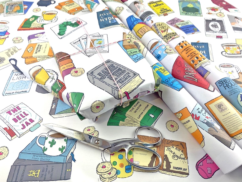 May include: White wrapping paper with a colorful pattern of books, teacups, and biscuits. The paper features titles like "Jane Eyre", "The Bell Jar", "To Kill a Mockingbird", and "The Two Towers".