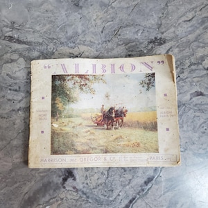 Op de afbeelding: Een rechthoekige papieren advertentie met de tekst ALBION in grote letters. Het midden toont een kleurenillustratie van twee paarden die een oogstmachine door een veld trekken. De tekst onderaan luidt HARRISON, Mc GREGOR & C, PARIS.