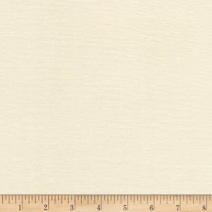 Pu&ograve; includere: Tessuto color crema con una sottile trama intrecciata. Il tessuto &egrave; di colore neutro e uniforme. Un righello di legno si trova nella parte inferiore dell'immagine, con misure in pollici.