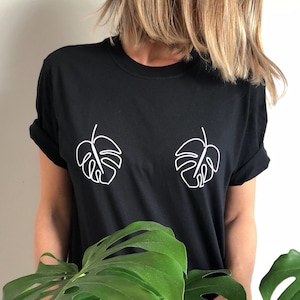 May include: A black t-shirt with a white outline of two monstera leaves on the front.