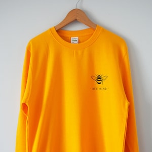 May include: A yellow sweatshirt with a black bee graphic and the text "BEE KIND" on the front.