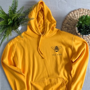 May include: A yellow hoodie with a black bee graphic and the text "BEE KIND" on the front.