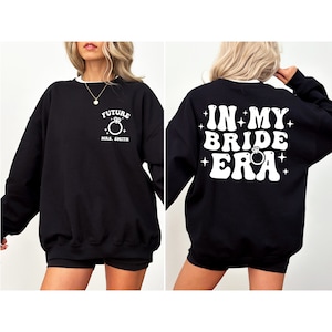 May include: Black sweatshirt with white text that says "Future Mrs. Smith" on the front and "In My Bride Era" on the back. The text is in a retro font with a ring and diamond graphic.