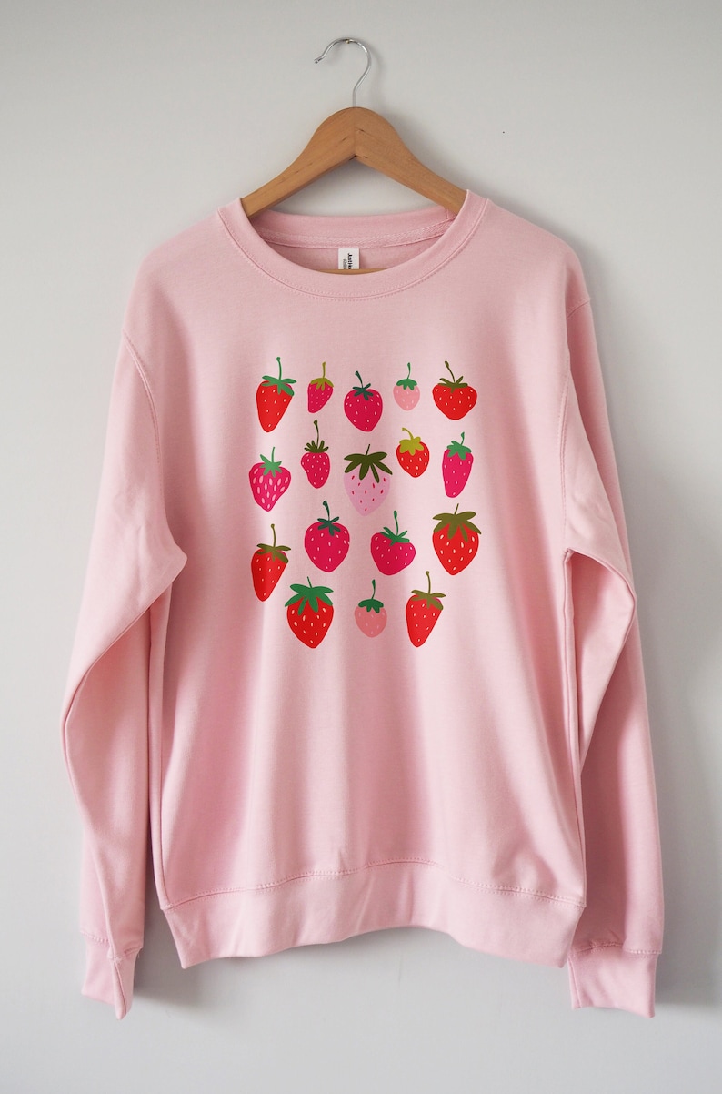 May include: A pink sweatshirt with a pattern of red and green strawberries.