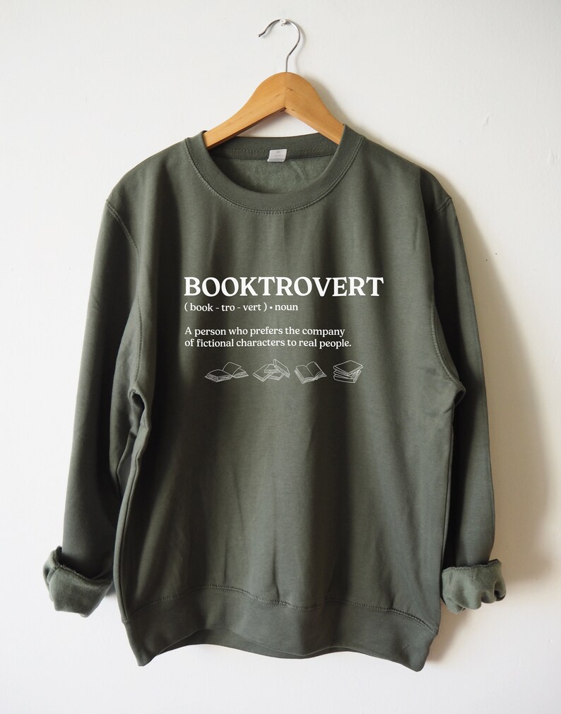 May include: A green sweatshirt with the word "BOOKTROVERT" printed on the front. The word is defined as "(book - tro - vert). noun A person who prefers the company of fictional characters to real people."
