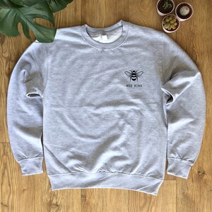 May include: A gray sweatshirt with a black bee graphic and the text "Bee Kind" on the front.