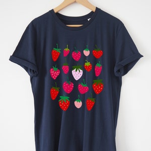 Puede incluir: Una camiseta azul marino con un patr&oacute;n de fresas rojas, rosas y verdes.