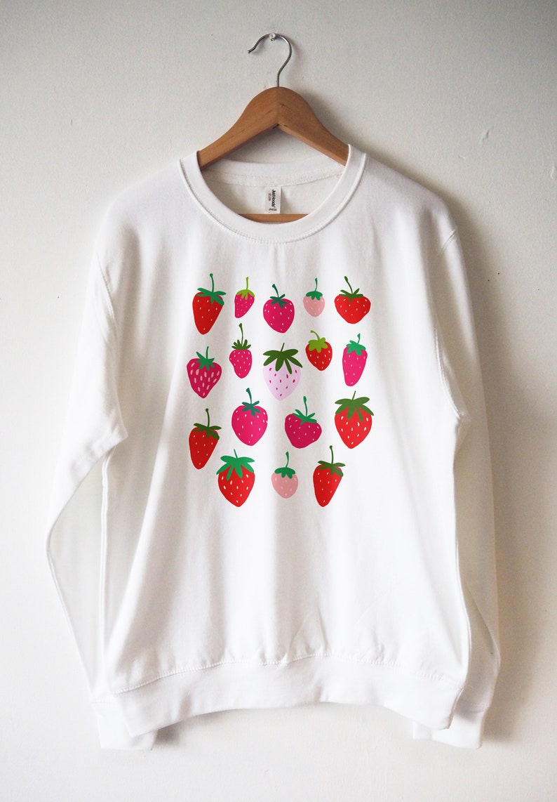 May include: White sweatshirt with a pattern of red, pink and green strawberries.