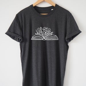 May include: A dark heather grey t-shirt with a white graphic of an open book with flowers growing from it.