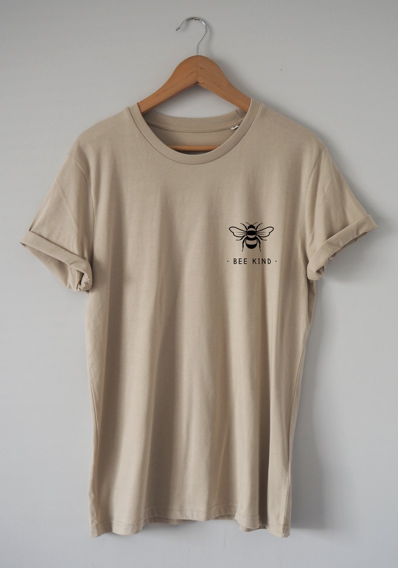 May include: A beige t-shirt with a black bee graphic and the text "BEE KIND" on the front.