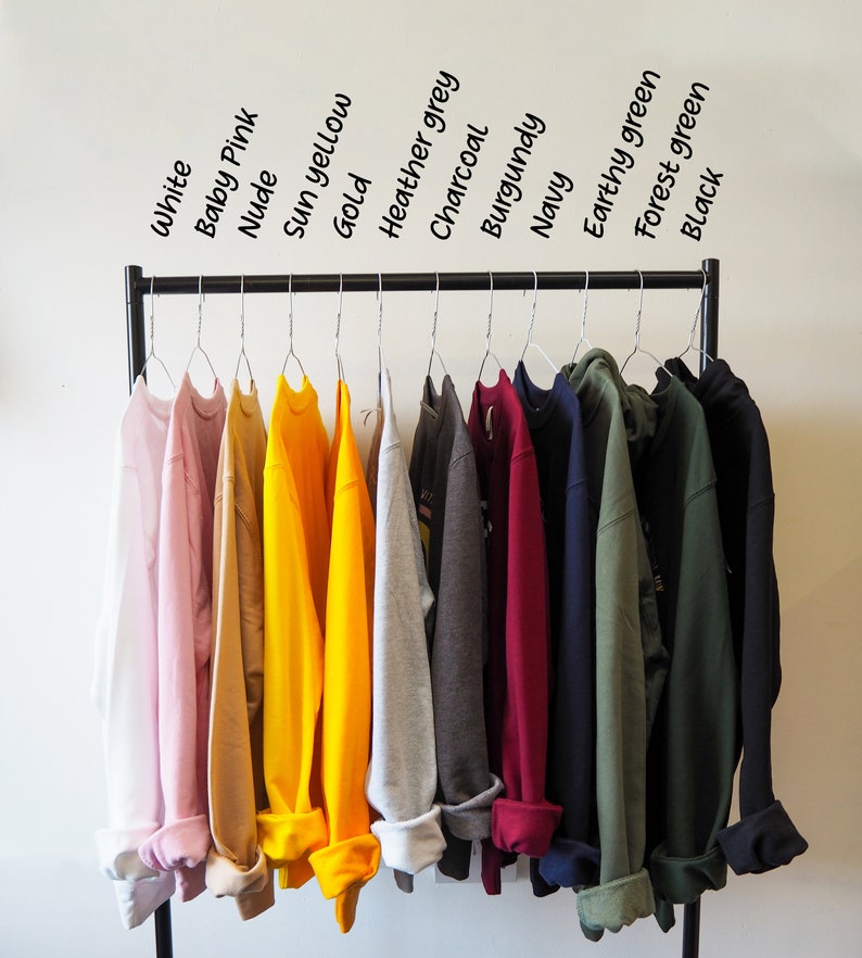 May include: A rack of 12 sweatshirts in various colours, including white, baby pink, nude, sun yellow, gold, heather grey, charcoal, burgundy, navy, earthy green, forest green, and black.