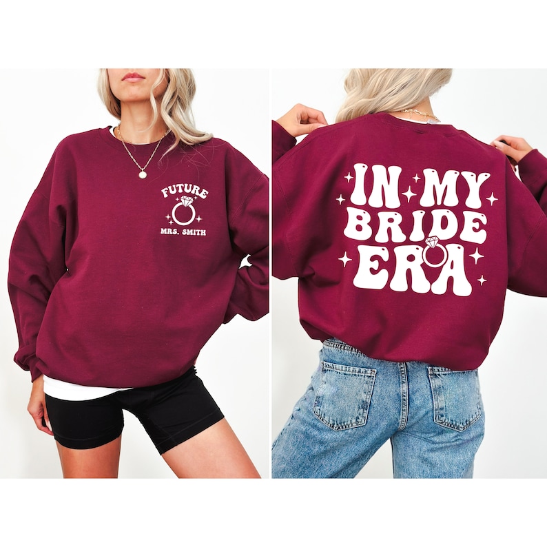 May include: Burgundy sweatshirt with white text that says "Future Mrs. Smith" on the front and "In My Bride Era" on the back. The text is in a retro font with a diamond ring graphic.