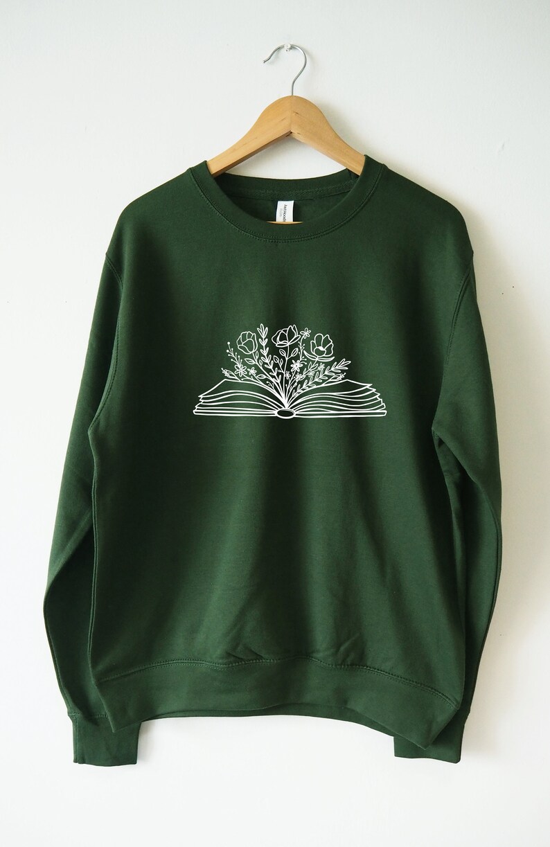 May include: A dark green sweatshirt with a white outline of an open book with flowers growing out of it.