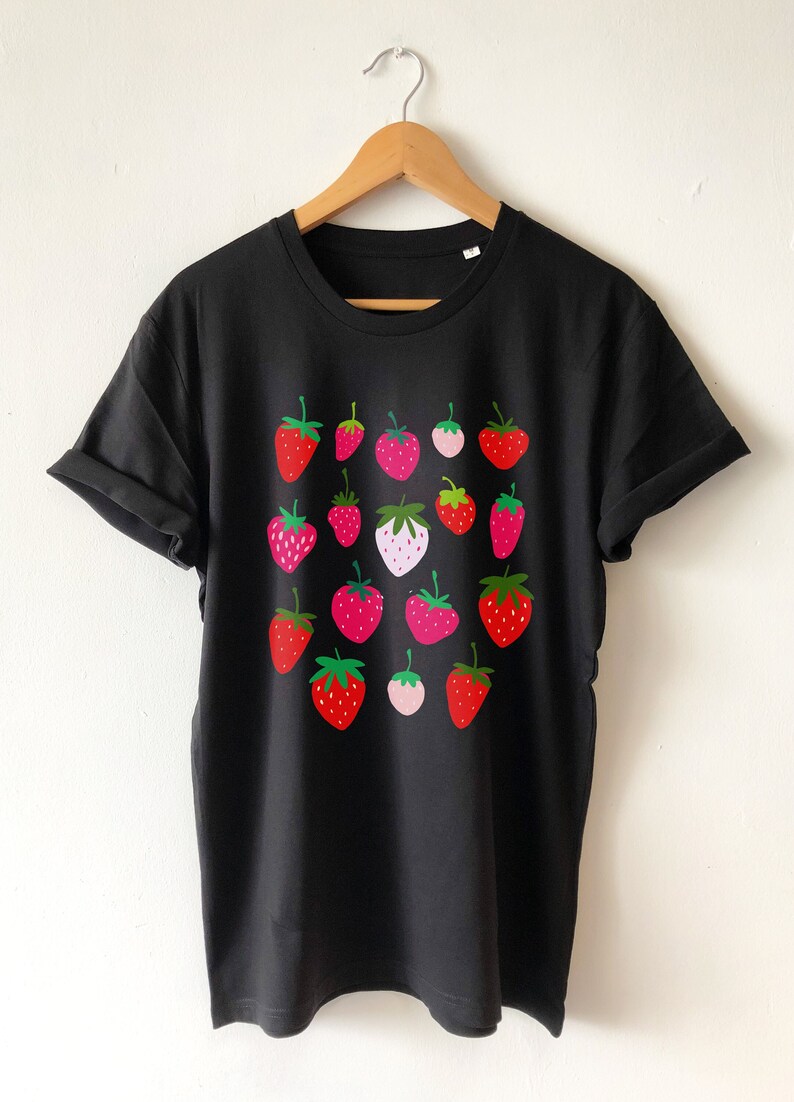 Puede incluir: Camiseta negra con estampado gr&aacute;fico de fresas rojas, rosas y verdes.
