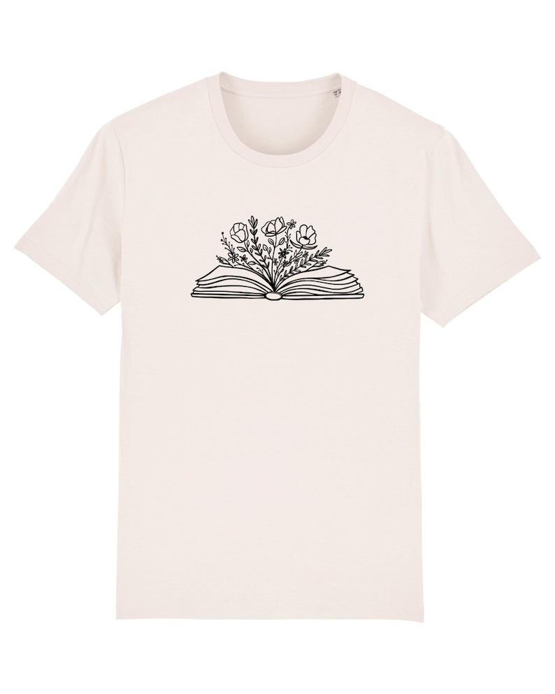 May include: A white t-shirt with a black line drawing of an open book with flowers growing out of it.
